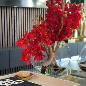 Cymbidiums rojos en jarrón Moon